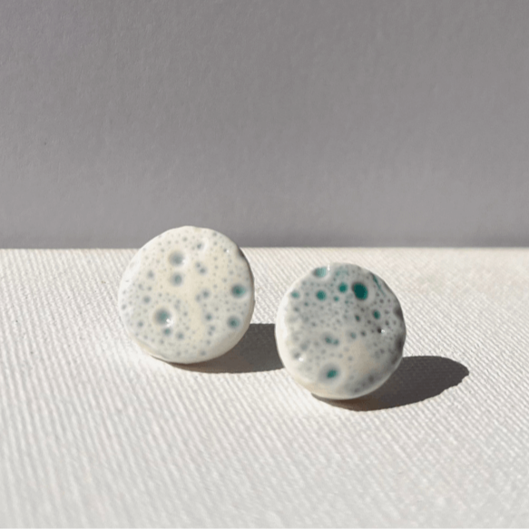 Close-up of handcrafted porcelain stud earrings with sea urchin pattern, 1.5 cm in size, light and durable, inspired by coastal textures