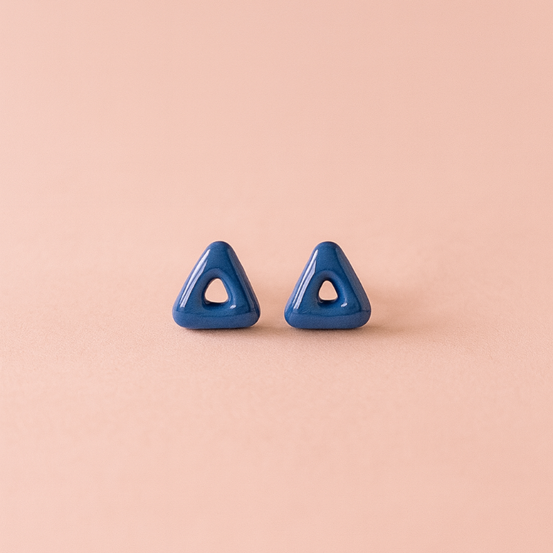 Close-up of shiny cobalt triangle studs with arrow-inspired design