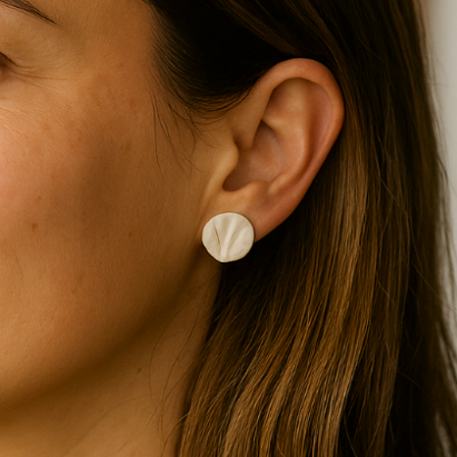 A pair of white porcelain coral-textured stud earrings displayed on a model close-up.