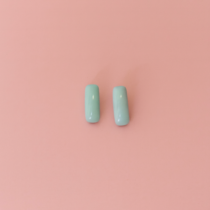 Handcrafted porcelain turquoise blue stud earrings on soft pink background