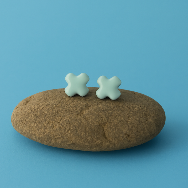 Minimalist lagoon porcelain turquoise cross stud earrings displayed on a stone prop