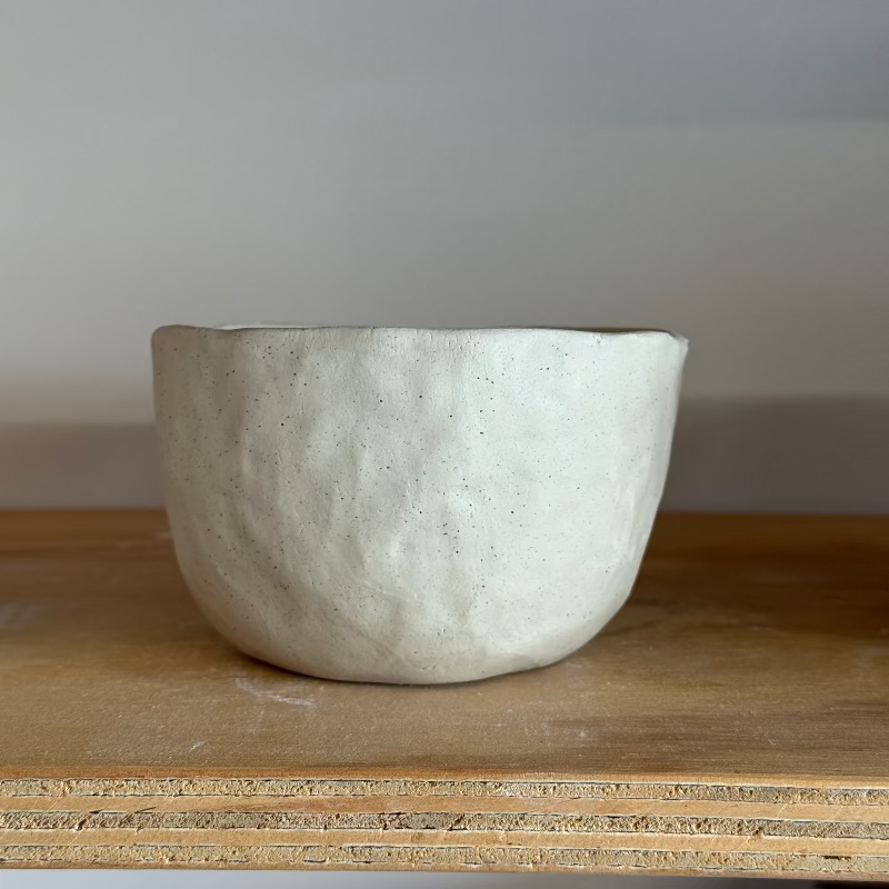 White ceramic bowl on a wooden surface with a plain background