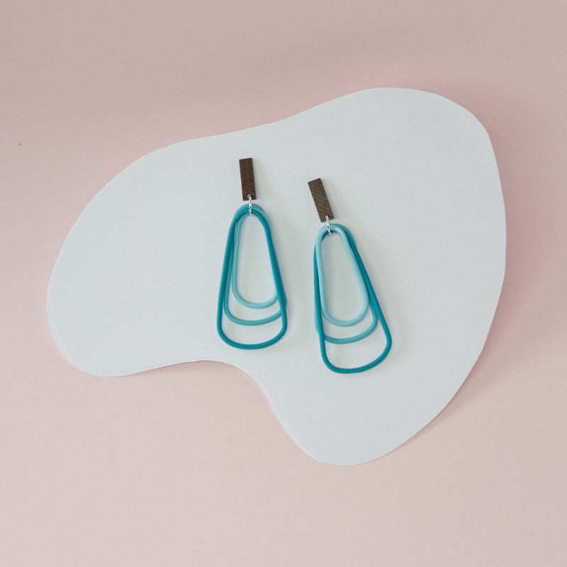 Bold teal dangles that capture the depth and energy of the ocean in every movement.