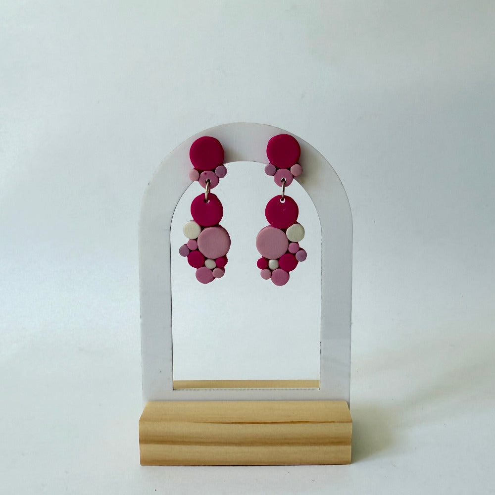 Handmade polymer-clay monochromatic pink bubble clusters with surgical-steel studs, displayed on a light background.