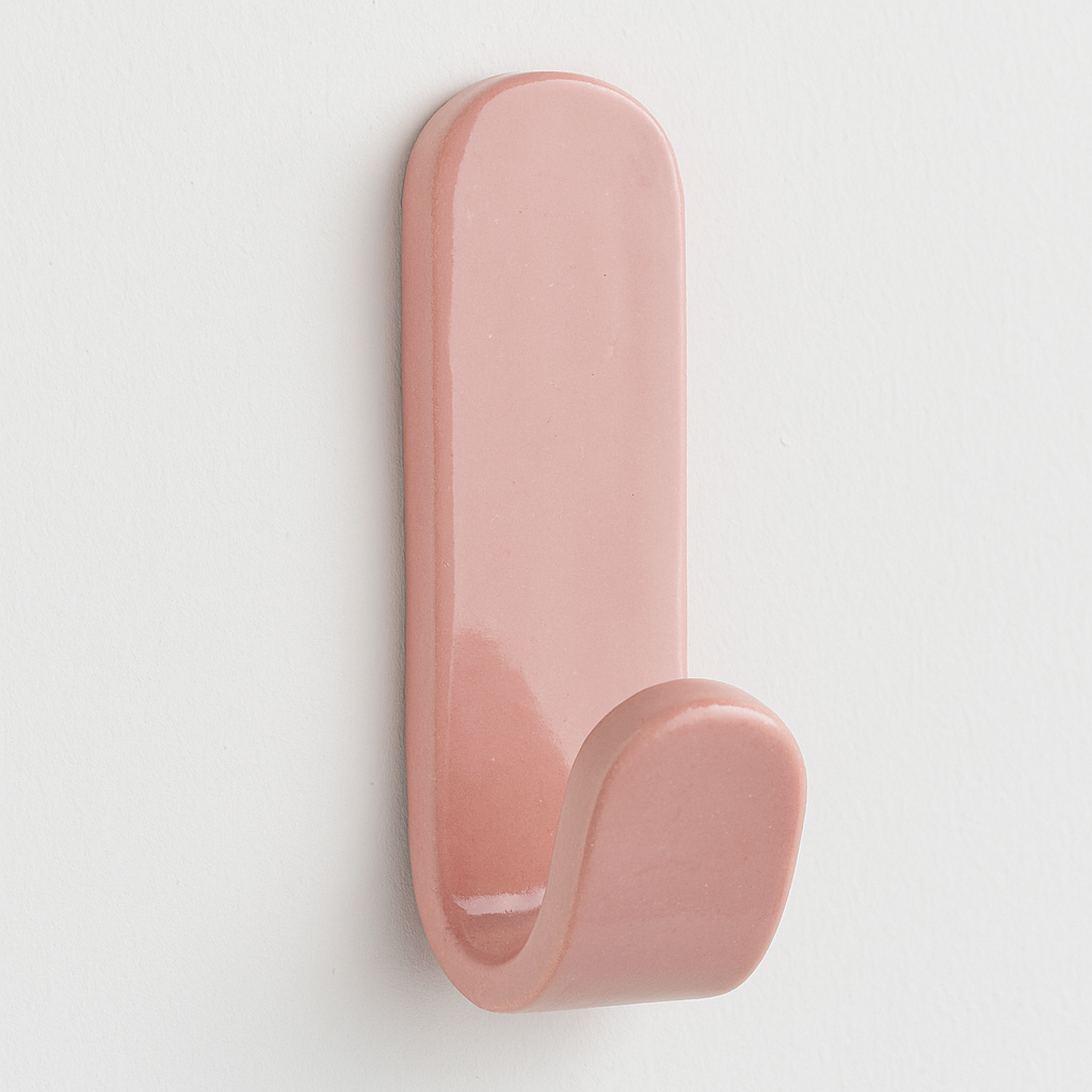 Pink stoneware wall hook on white wall – coastal-inspired handmade bedroom decor.