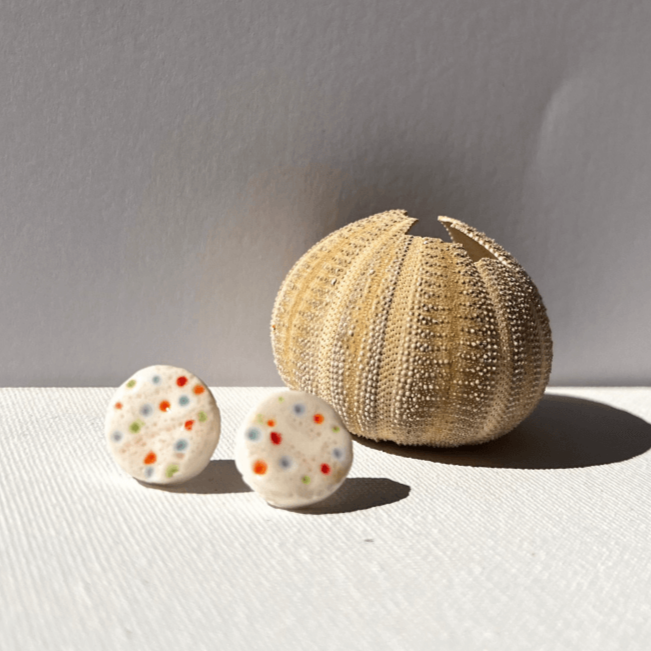 Close-up of handcrafted porcelain stud earrings with sea urchin pattern, 1.5 cm in size, light and durable, inspired by coastal textures.