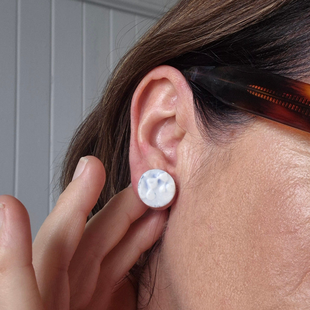 Woman wearing blue porcelain seaweed studs.