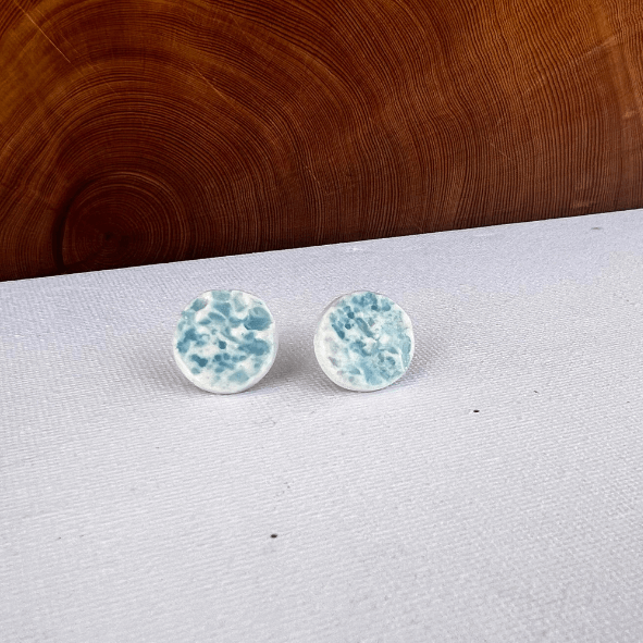Porcelain sea pebble stud earrings on white canvas background with turquoise marbled glaze pattern.