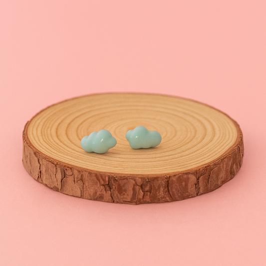 Pair of turquoise cloud-shaped earrings on a wooden platform with a pink background