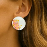Porcelain stud earrings hand-painted with pink paper daisies and yellow billy buttons, displayed on model