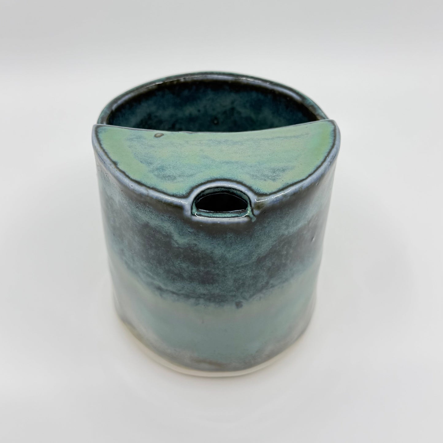 Handmade stoneware coffee cup with layered ocean-inspired blue and seafoam glazes, inspired by the deep blue sea and coastal landscapes.