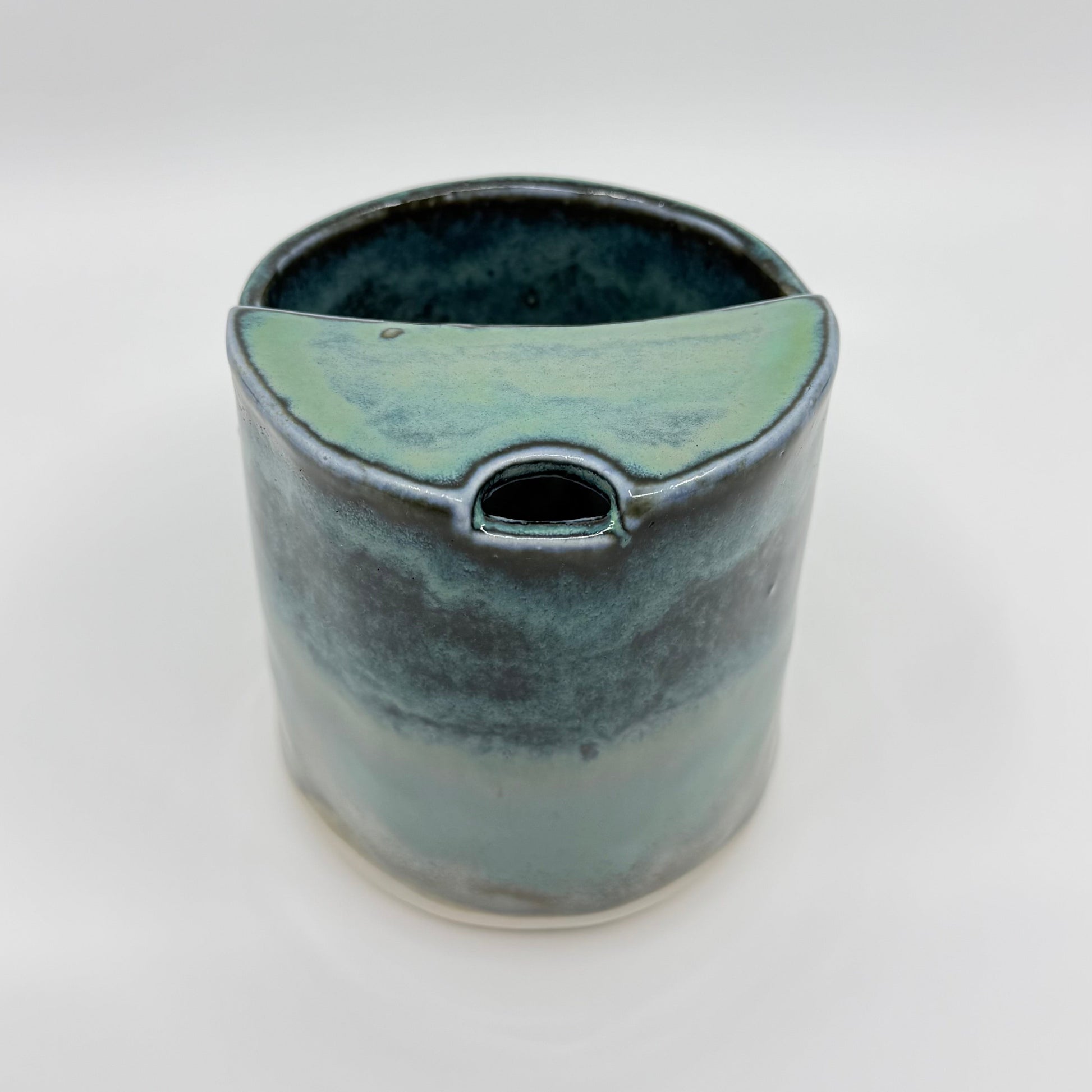 Handmade stoneware coffee cup with layered ocean-inspired blue and seafoam glazes, inspired by the deep blue sea and coastal landscapes.