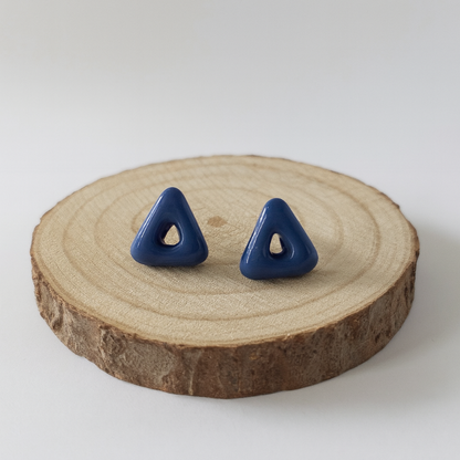 Blue triangle-shaped earrings on a wooden slice with a white background