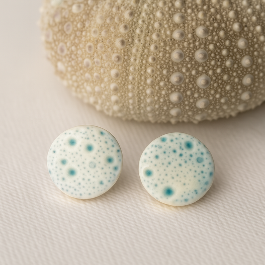 Close-up of handcrafted porcelain stud earrings with sea urchin pattern, 1.5 cm in size, light and durable, inspired by coastal textures.