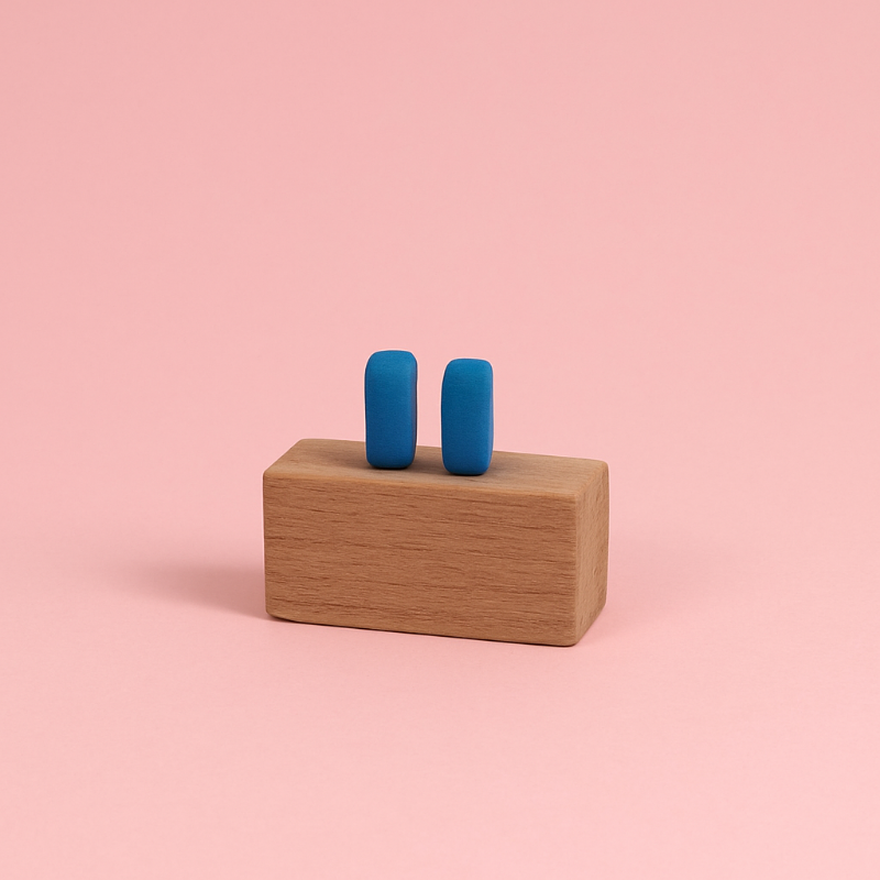 Handmade matte blue porcelain bar earrings displayed on wooden prop