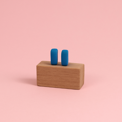 Handmade matte blue porcelain bar earrings displayed on wooden prop