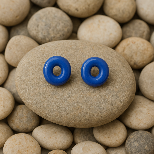 Blue porcelain circle studs resting on a beach stone with natural texture