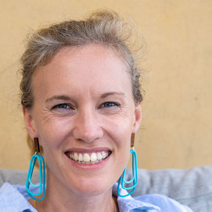 Woman wearing monochromatic teal dangle earrings. Light and easy wearing. 
