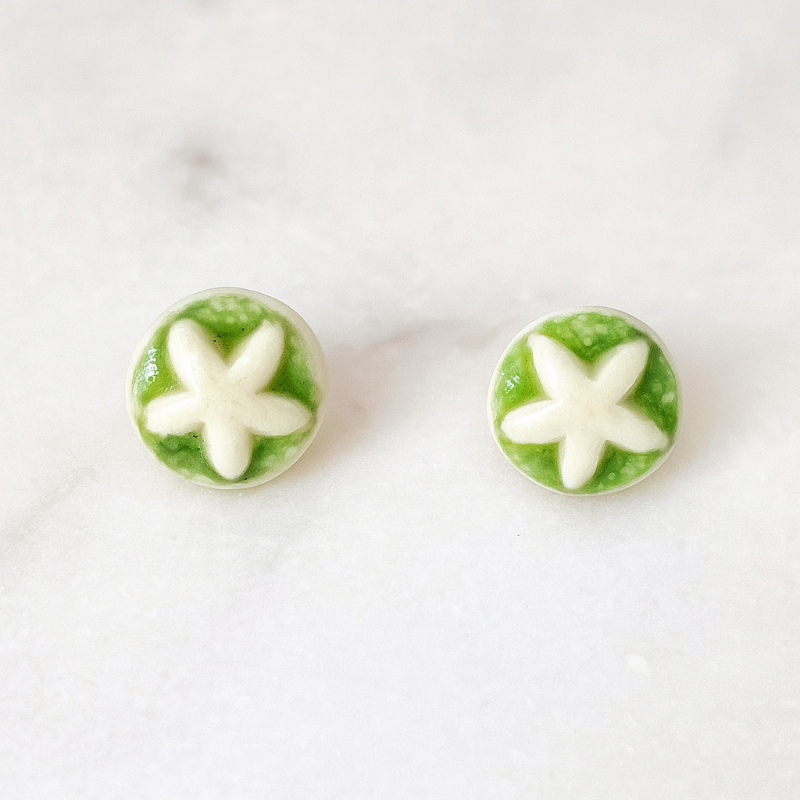 A pair of handmade porcelain stud earrings with organic star-shaped impressions, glazed in apple green.