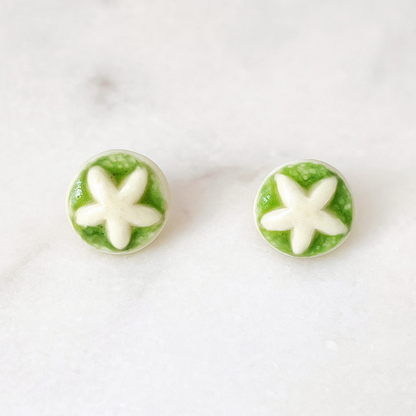 A pair of handmade porcelain stud earrings with organic star-shaped impressions, glazed in apple green.
