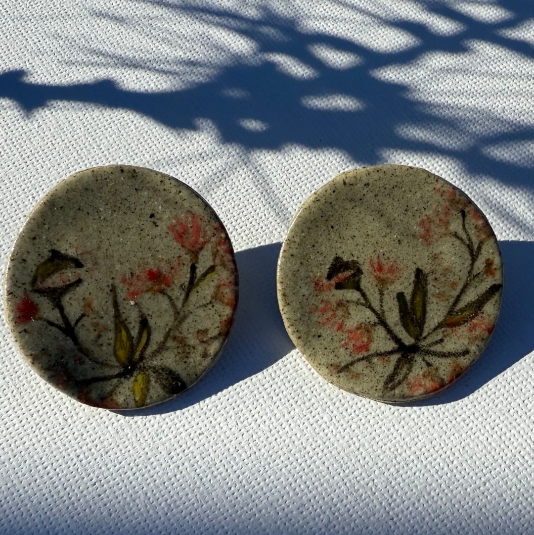 Pair of round handcrafted ceramic earrings painted with Australian gum leaves, blossoms, and gumnuts on speckled clay, 3.5 cm wide.