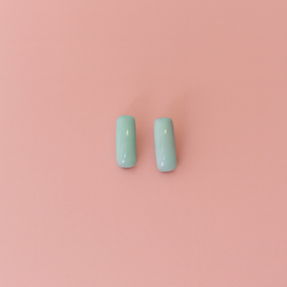 Handcrafted porcelain turquoise blue stud earrings on soft pink background