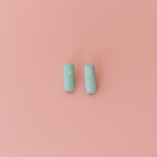 Handcrafted porcelain turquoise blue stud earrings on soft pink background