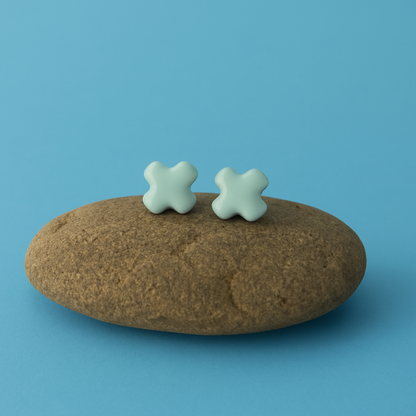 Minimalist lagoon porcelain turquoise cross stud earrings displayed on a stone prop