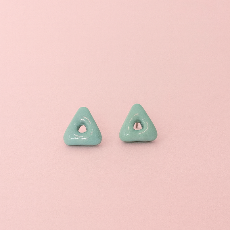Lagoon turquoise blue porcelain arrow stud earrings on soft pink background