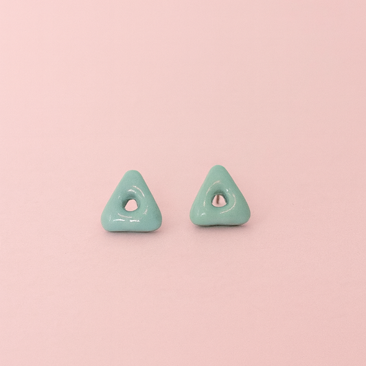 Lagoon turquoise blue porcelain arrow stud earrings on soft pink background