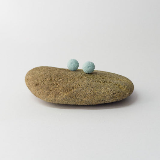 Close-up of handcrafted sea urchin studs in laguna porcelain with textured detail
