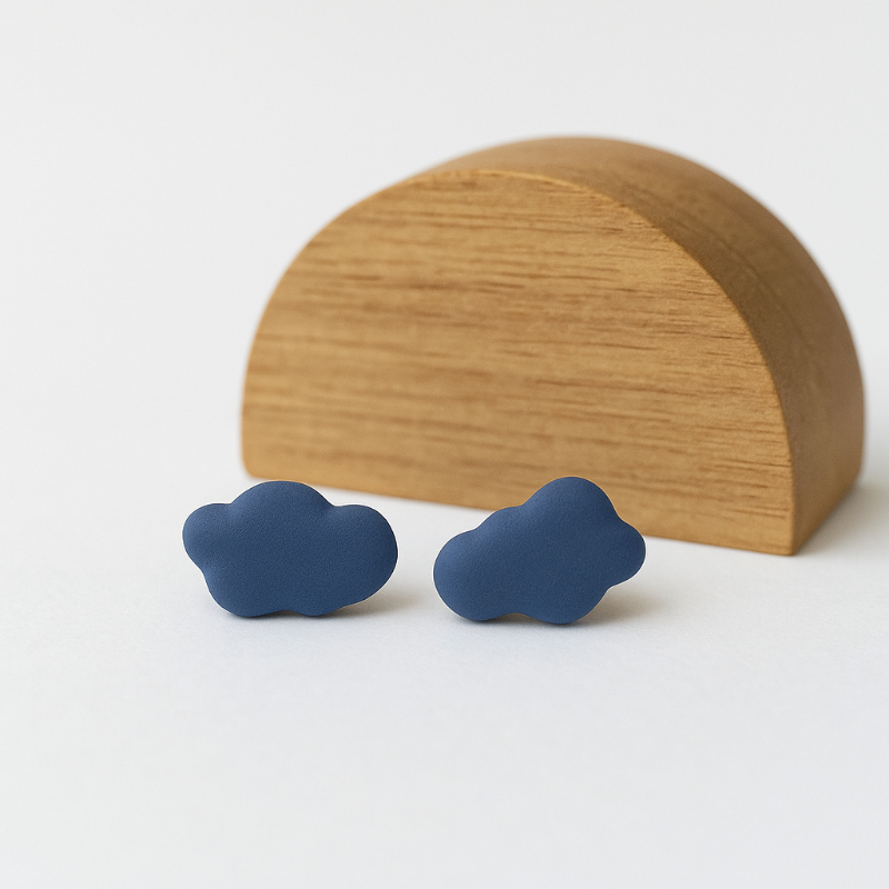Pair of handcrafted cobalt blue porcelain cloud earrings against neutral background