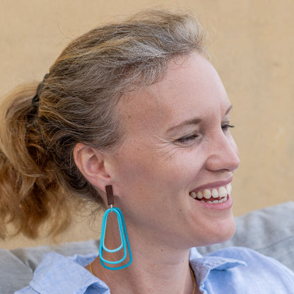 Woman wearing monochromatic teal dangle earrings. Light and easy wearing. 