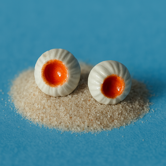 Pair of handmade porcelain earrings shaped like sea anemones, featuring white rippled edges and a bold orange center.