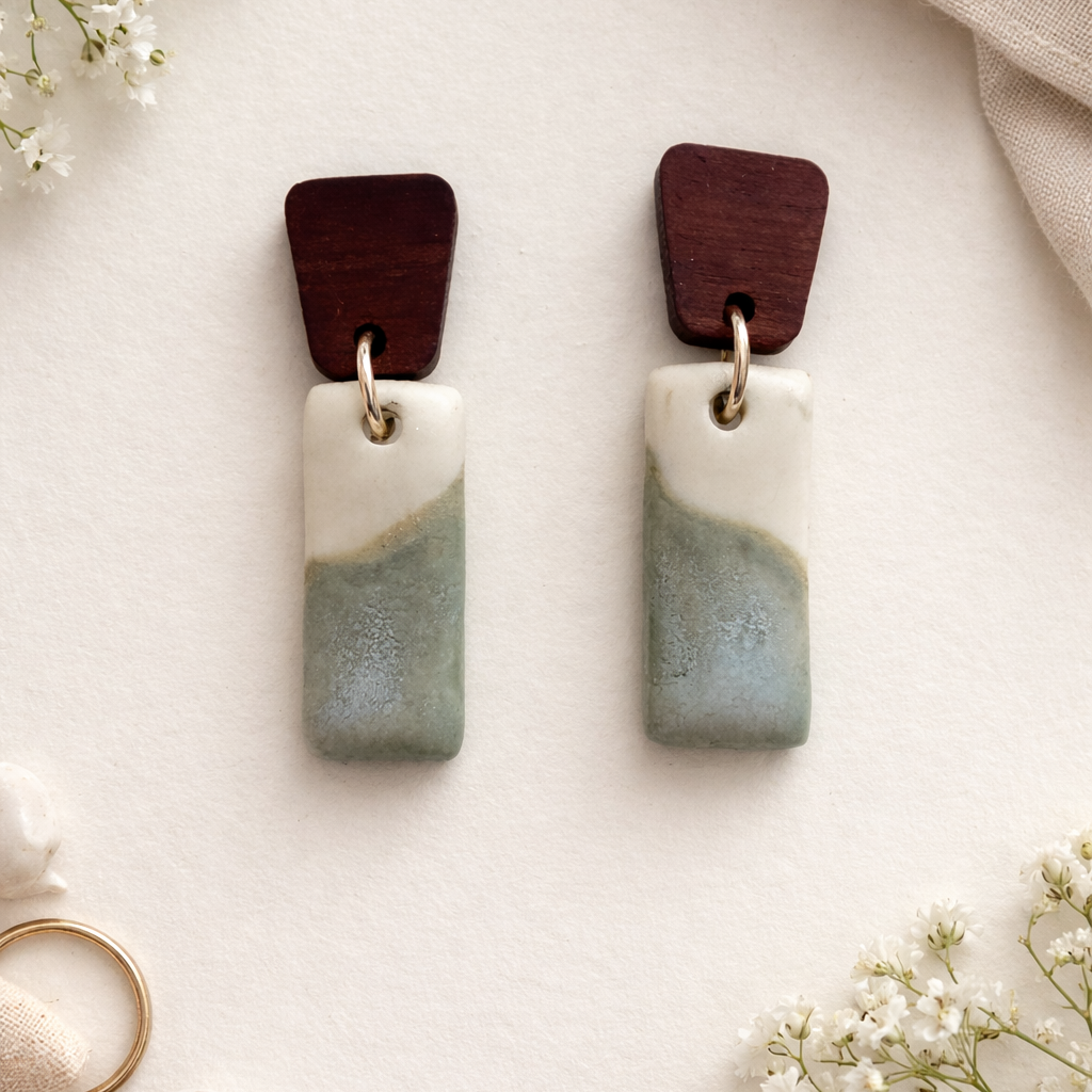 Handmade porcelain dangle earrings with seafoam green glaze and wooden tops on white background