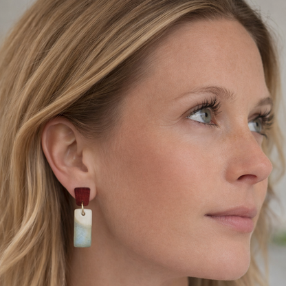 Close-up of handcrafted ceramic earrings with wooden stud tops and ocean-inspired glaze