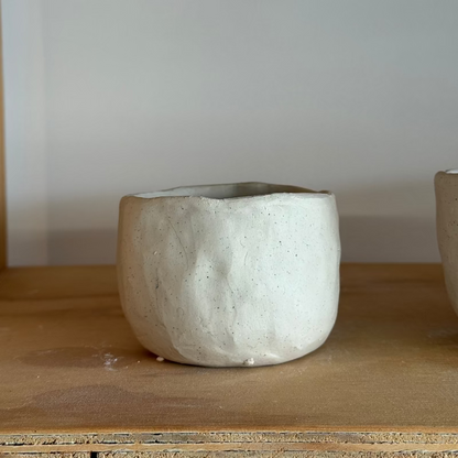 White ceramic pot on a wooden surface with a plain background