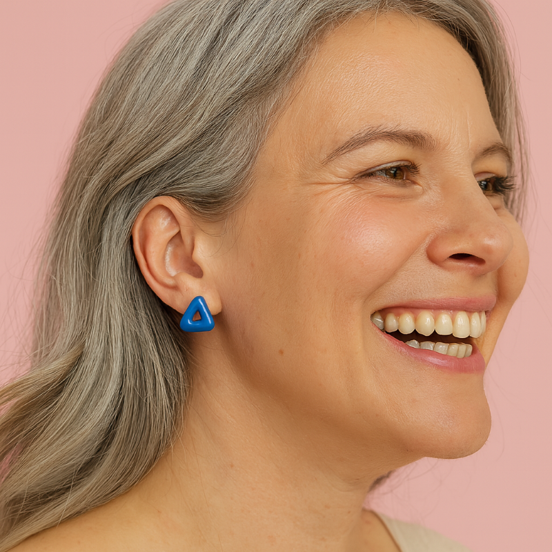 Woman wearing a blue triangle earring against a pink background