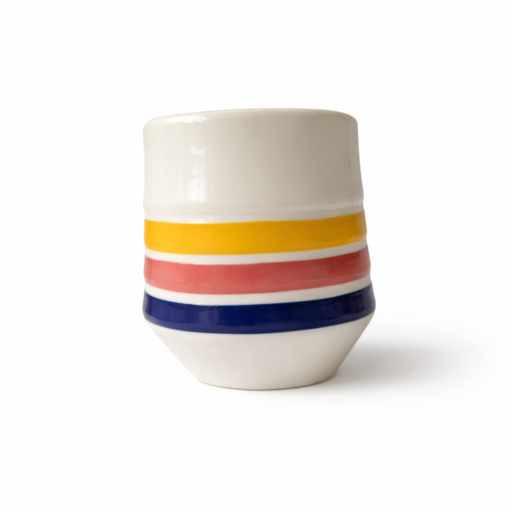 Unique striped porcelain cup reflecting morning light on a beach