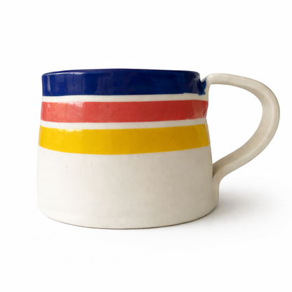 Hand-painted porcelain cup with colourful sunrise stripes on white background