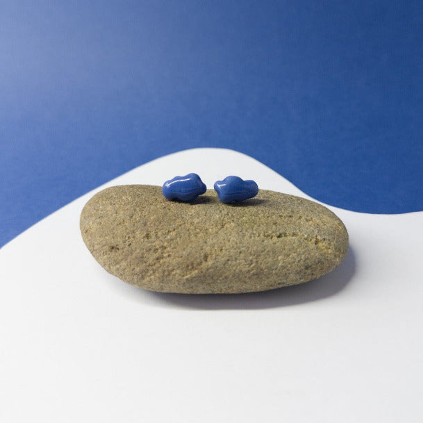 Flat lay of blue porcelain cloud-shaped earrings on a light surface