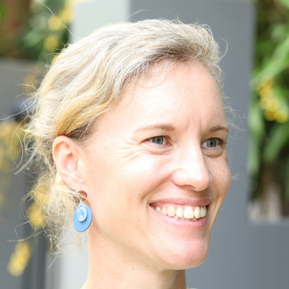 Woman wearing fingerprints of nature blue coral texture porcelain earrings. 