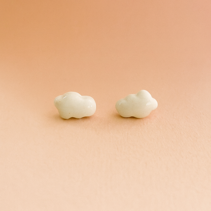 Close-up of handmade white porcelain cloud stud earrings on a neutral background