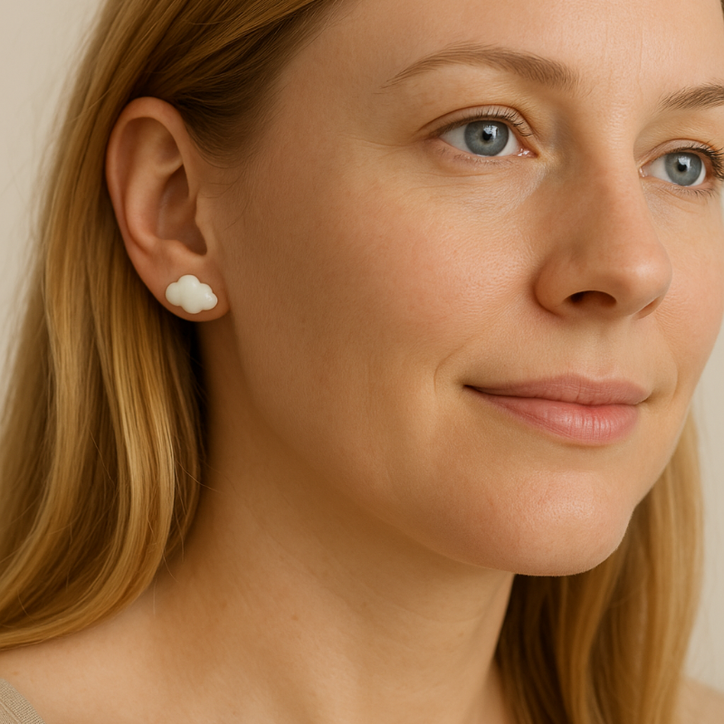 Close-up of a woman wearing a small cloud earring with a neutral background