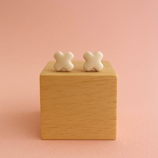 A pair of Tide + Form white porcelain cross stud earrings with a glossy finish, handcrafted and displayed on a clean background.