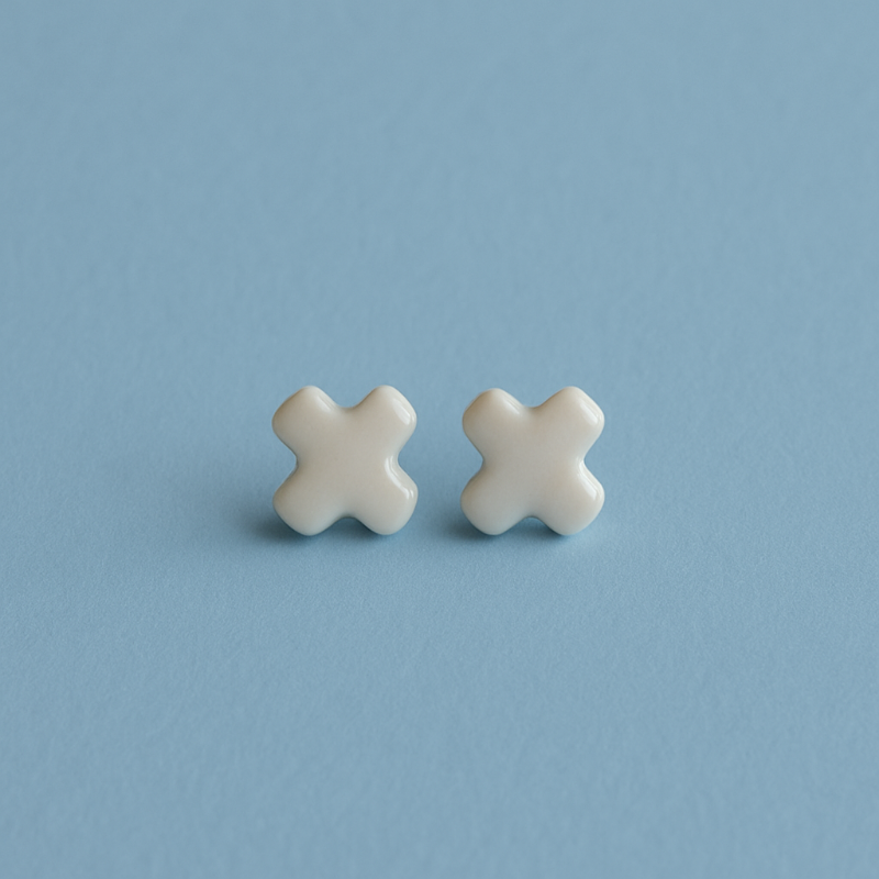 A pair of Tide + Form white porcelain cross stud earrings with a glossy finish, handcrafted and displayed on a clean background.