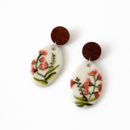 Hand-painted porcelain dangle earrings featuring a bursting gumnut design with wooden stud tops on a white background