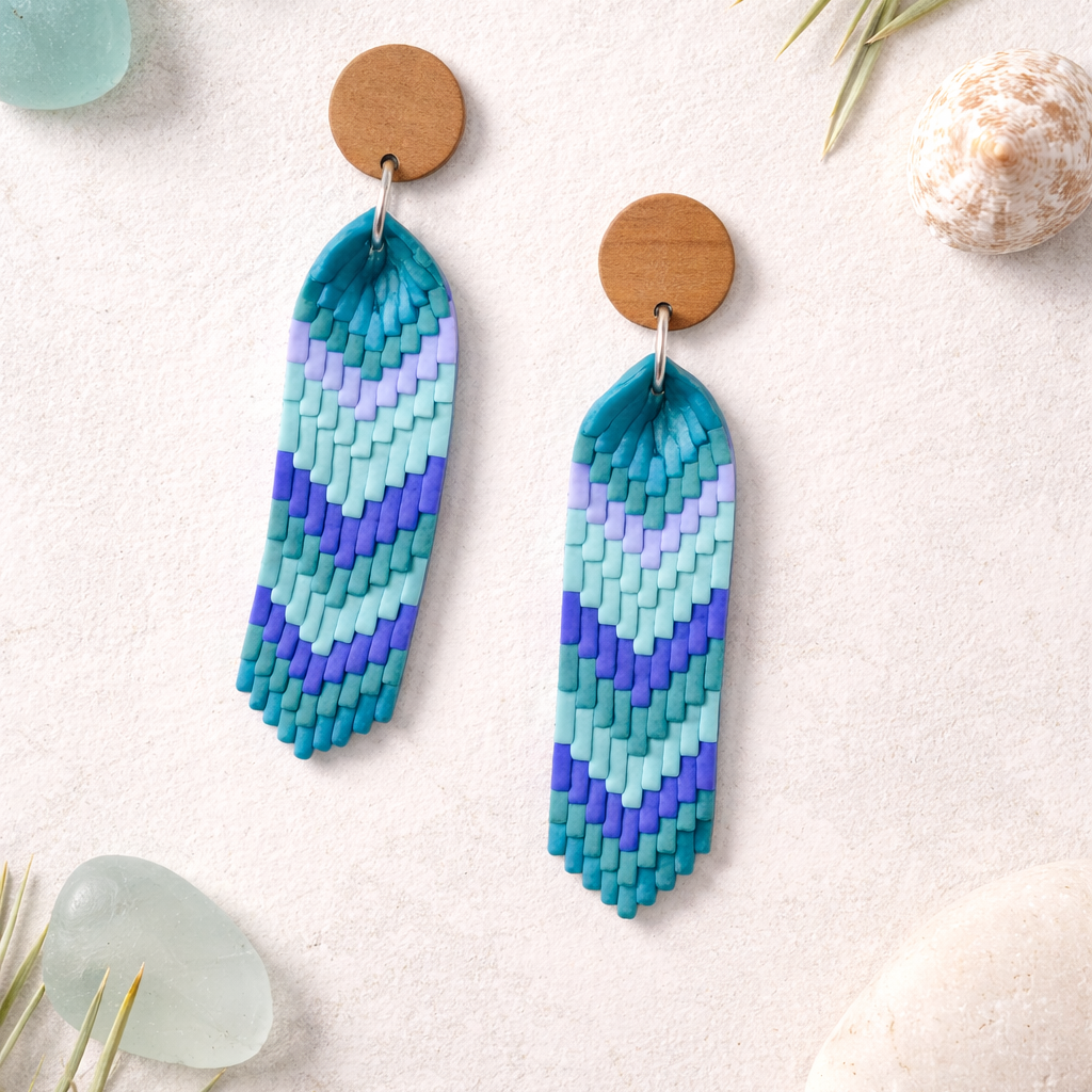 Handcrafted sea glass chevron polymer clay earrings in teal, aqua and blue gradient with wooden stud tops.