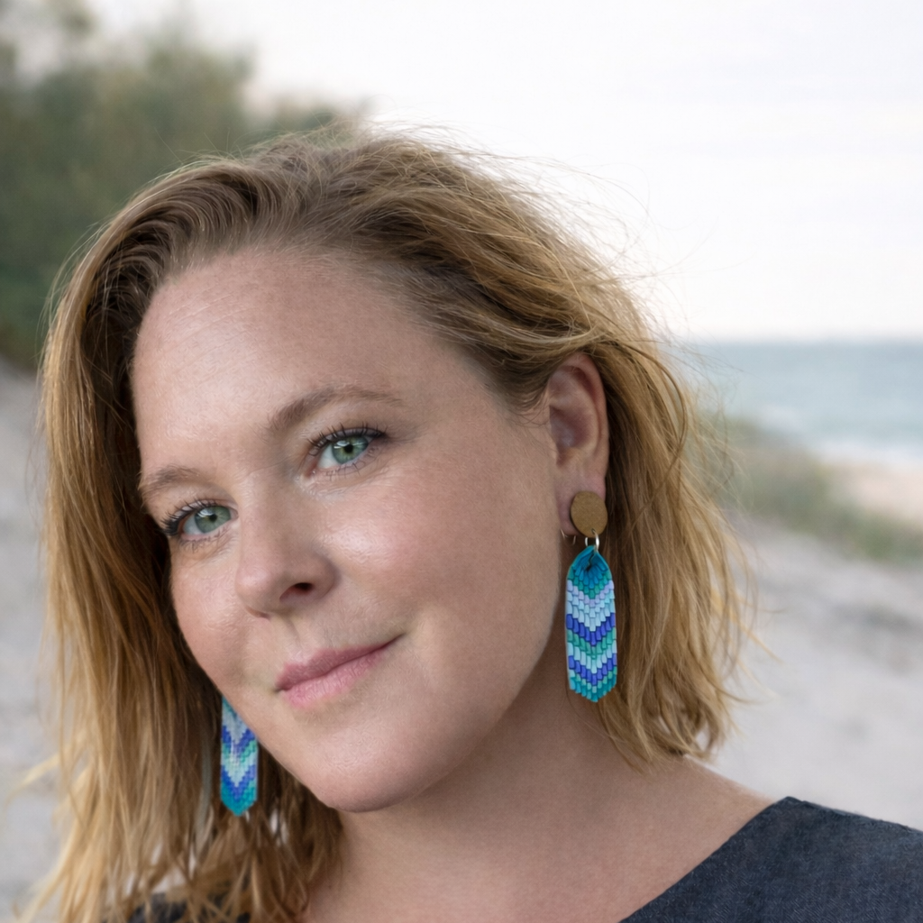 Woman wearing teal and blue sea glass chevron dangle earrings with wooden stud tops.